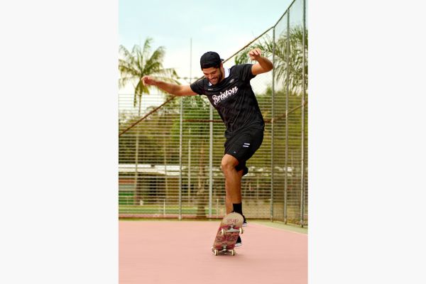 homem usa roupa fitness enquanto prática manobras de skate.