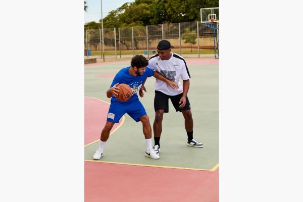 Dois homens jogam basquete em uma quadra.