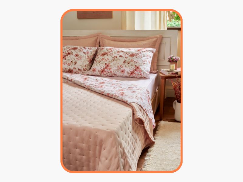 cama arrumada com uma colcha rosa