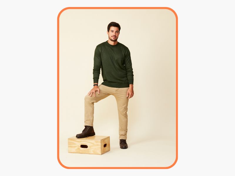 foto de homem com o pé apoiado sobre uma caixa usando suéter com coturno