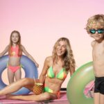 Mãe e filhos tirando foto com boias e oculos de praia