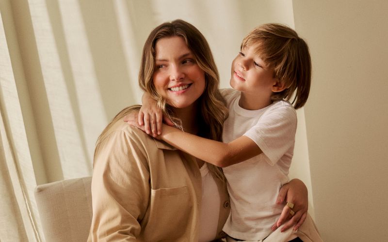 Mãe e filho sorrindo em ambiente aconchegante