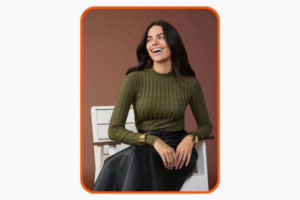 Mulher sorrindo com blusa verde e saia preta