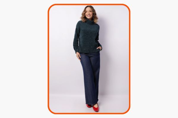 Mulher sorridente usando suéter verde e calça escura.