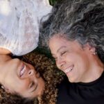 Duas mulheres sorrindo deitadas na grama
