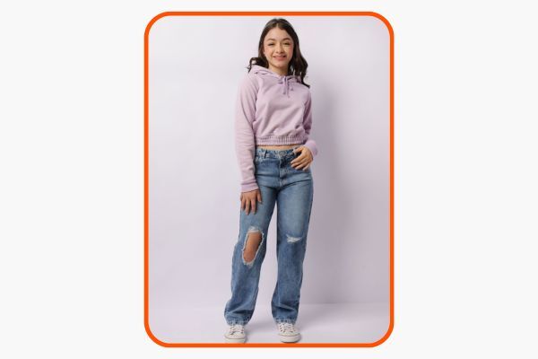 Menina sorrindo com moletom lilás e jeans rasgado.