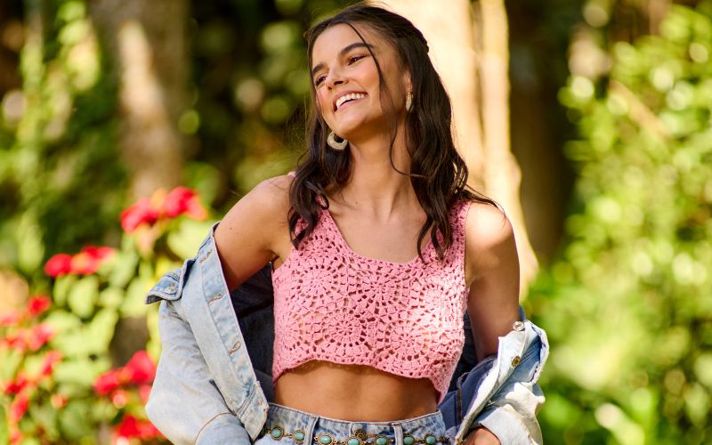 Jovem sorrindo com blusa de crochê rosa
