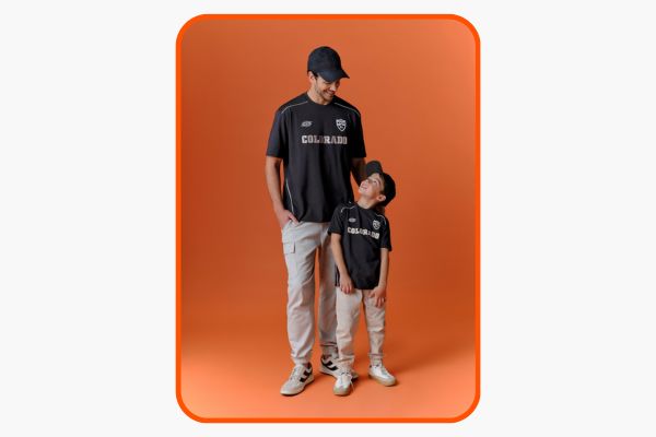 Pai e filho em roupas iguais, com fundo laranja.