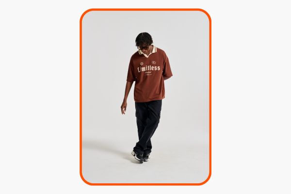 Homem veste camisa polo marrom com inspiração esportiva e calça preta.