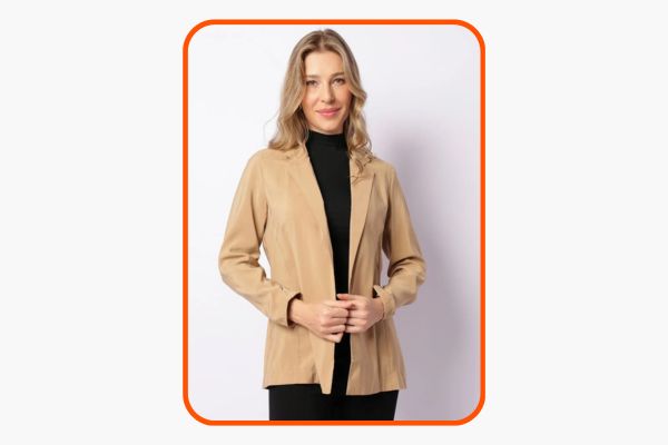 Mulher veste um blazer bege sobre um look preto.