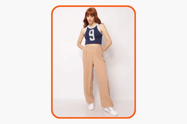 Mulher veste calça de alfaiaria wide leg bege com blusa azul com estilo esportivo