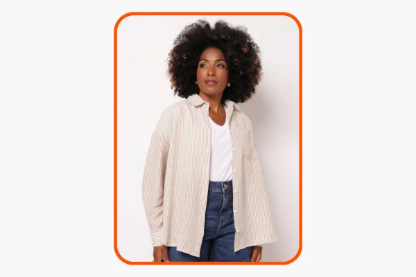 Mulher veste look com camisa oversized com listras brancas e marrom claro.