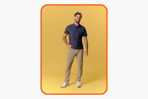 Homem veste camisa polo masculina azul escura com calça de sarja bege.