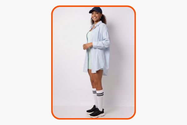 Mulher veste macaquinho fitness verde claro e por cima uma camisa oversized listrada de branco e azul. 