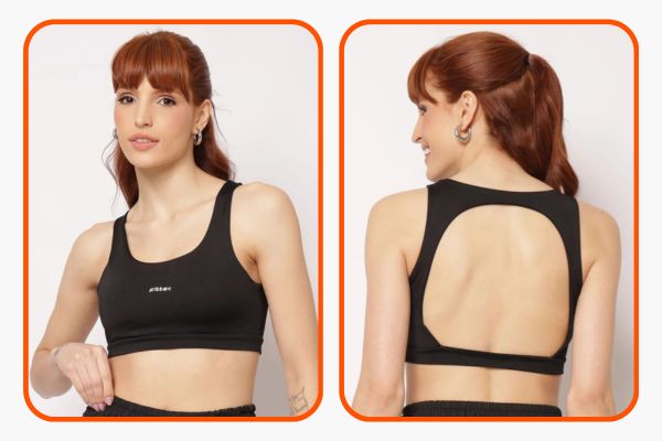 Modelo veste top fitness preto com decote V na frente e recorte nas costas, deixando a pele à mostra.