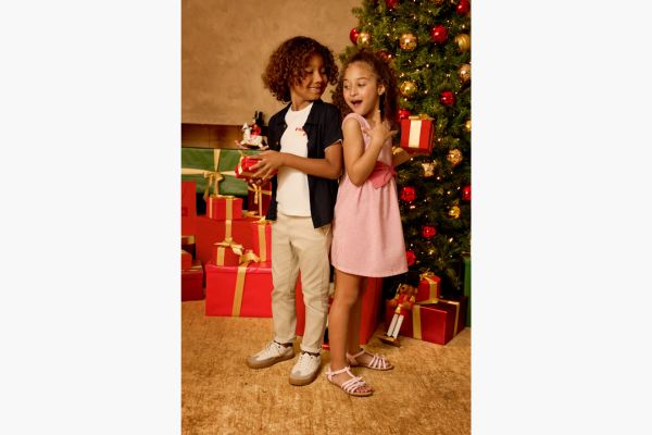 Crianças felizes com presentes ao lado da árvore de Natal