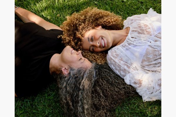 Duas mulheres sorrindo deitadas na grama
