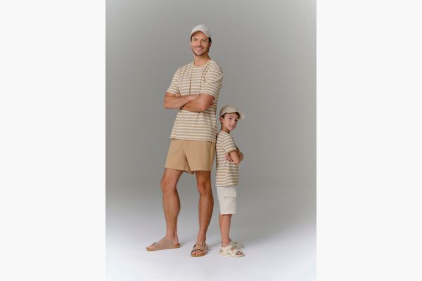 Pai e filho com roupas listradas em fundo neutro
