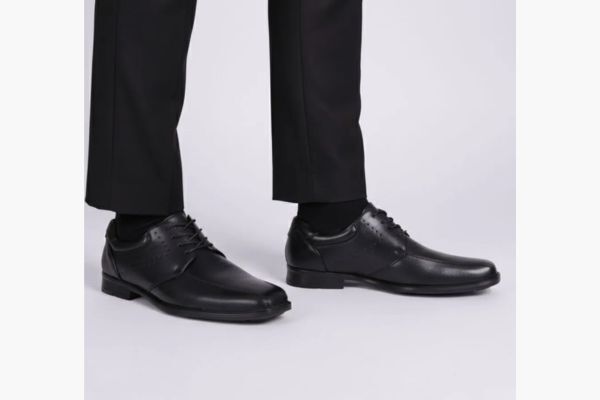 Sapatos sociais masculinos pretos em roupa formal.