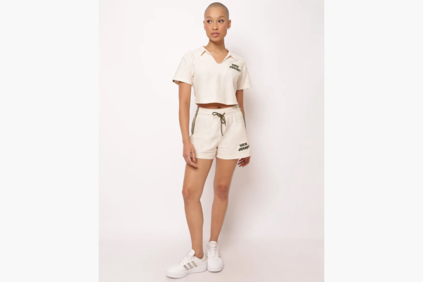 Modelo feminina com conjunto de moletom claro e tênis branco.