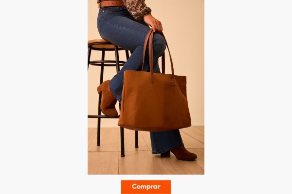 Pessoa segurando bolsa marrom em ambiente neutro