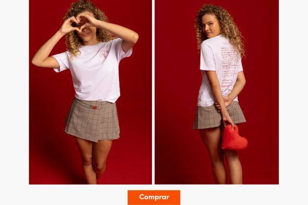 Modelo com camiseta e saia, formando coração com as mãos