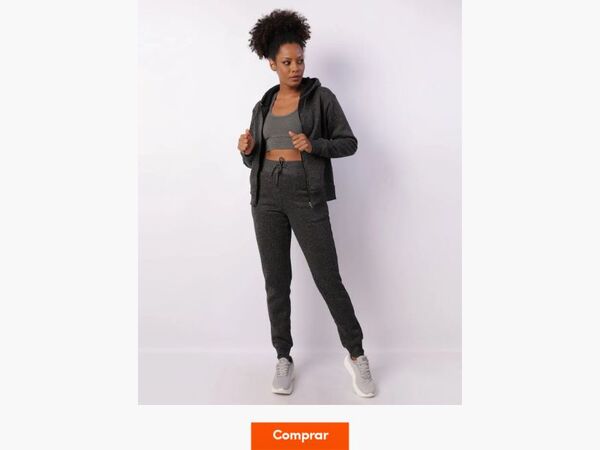 Mulher com outfit esportivo cinza posando em estúdio.