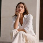 Modelo veste camisa e calça brancos com tecidos leves