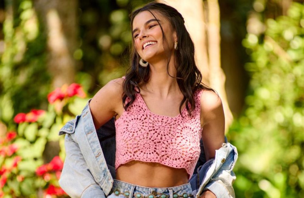 Jovem sorrindo com blusa de crochê rosa