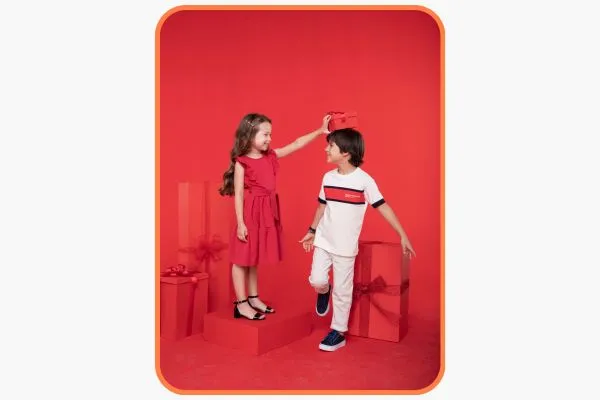 uma menina e um menino em um fundo vermelho no meio de algumas caixas de presentes vermelhas