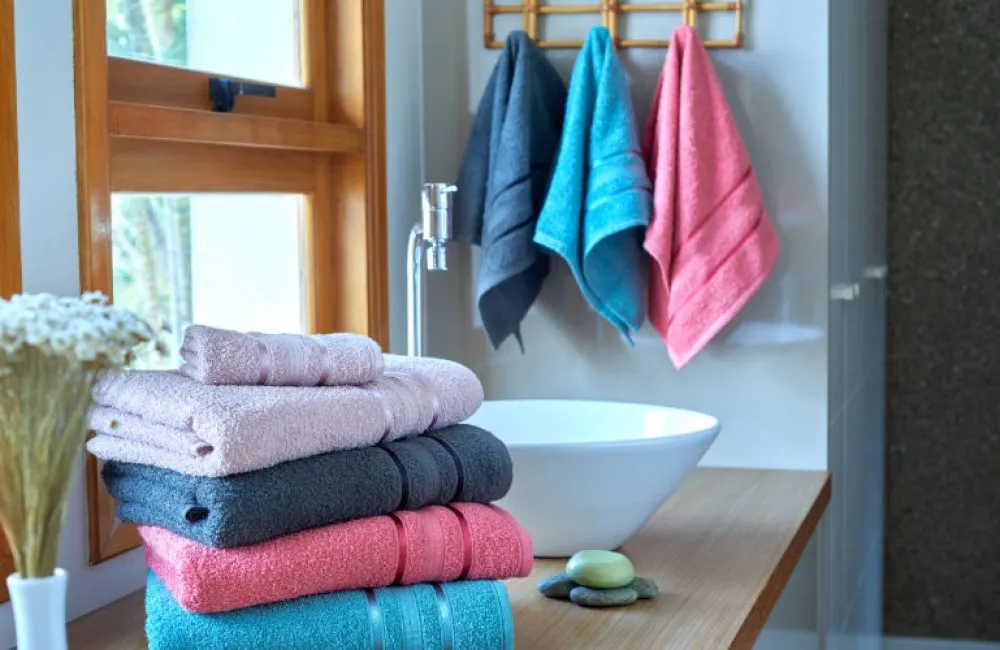 quatro toalhas sobre a pia do banheiro com uma parede de fundo